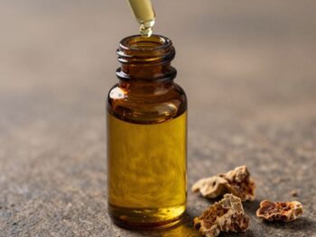 Bottle of golden frankincense oil with resin pieces.