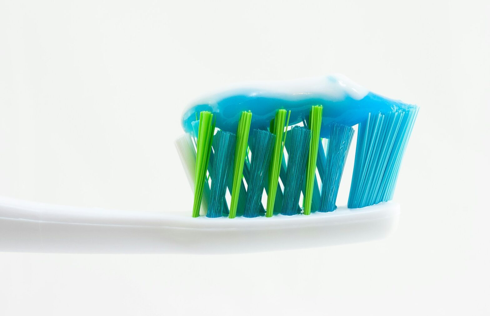 white, blue, and green toothbrush with blue toothpaste, clove oil for toothache