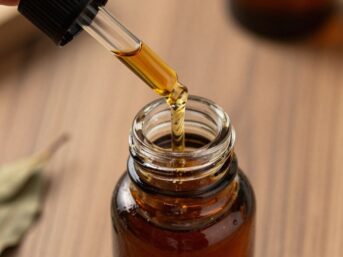 Patchouli oil in a dropper and vial with dried leaves.