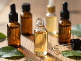 Bottles of essential oils with leaves on a wooden surface.